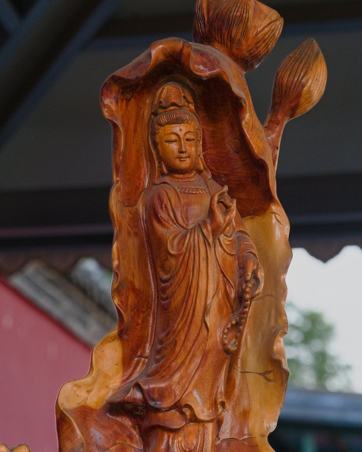 A hand-carved wooden statuette of a standing Buddhist figure