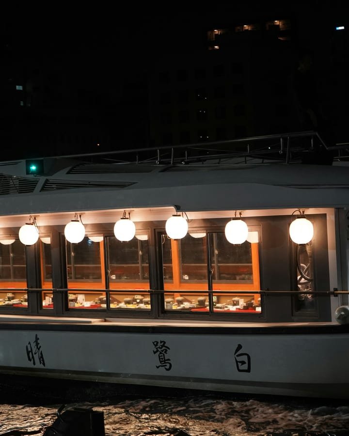 A lantern-lit Japanese pleasure boat on a river at night