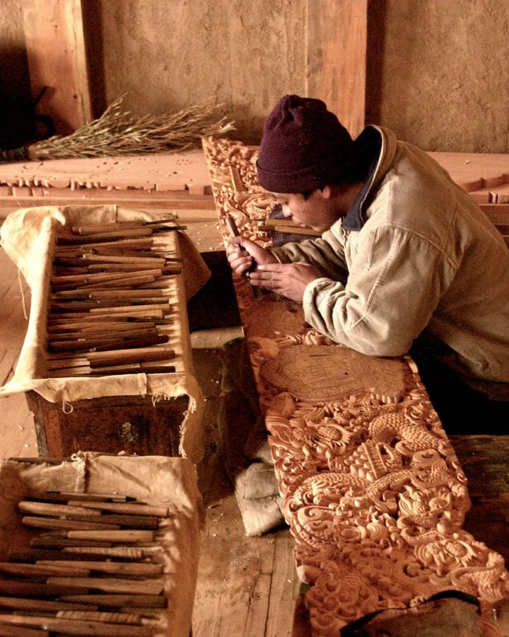 A craftsman carving a dragon relief in wood