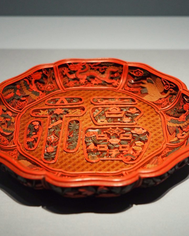 A carved red lacquer plate with an intricate raised pattern
