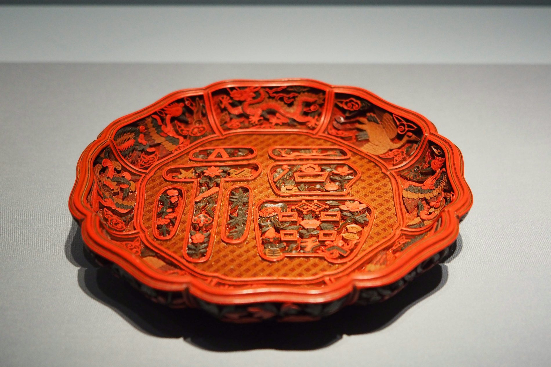 A carved red lacquer plate with an intricate raised pattern