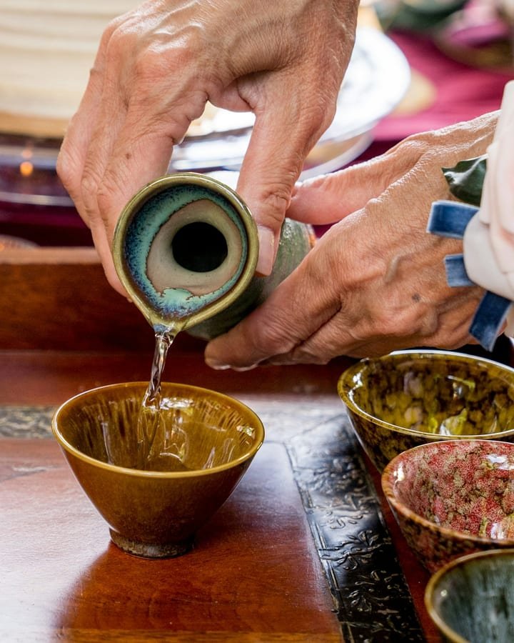 Sake being poured into ceramic cups at a tasting