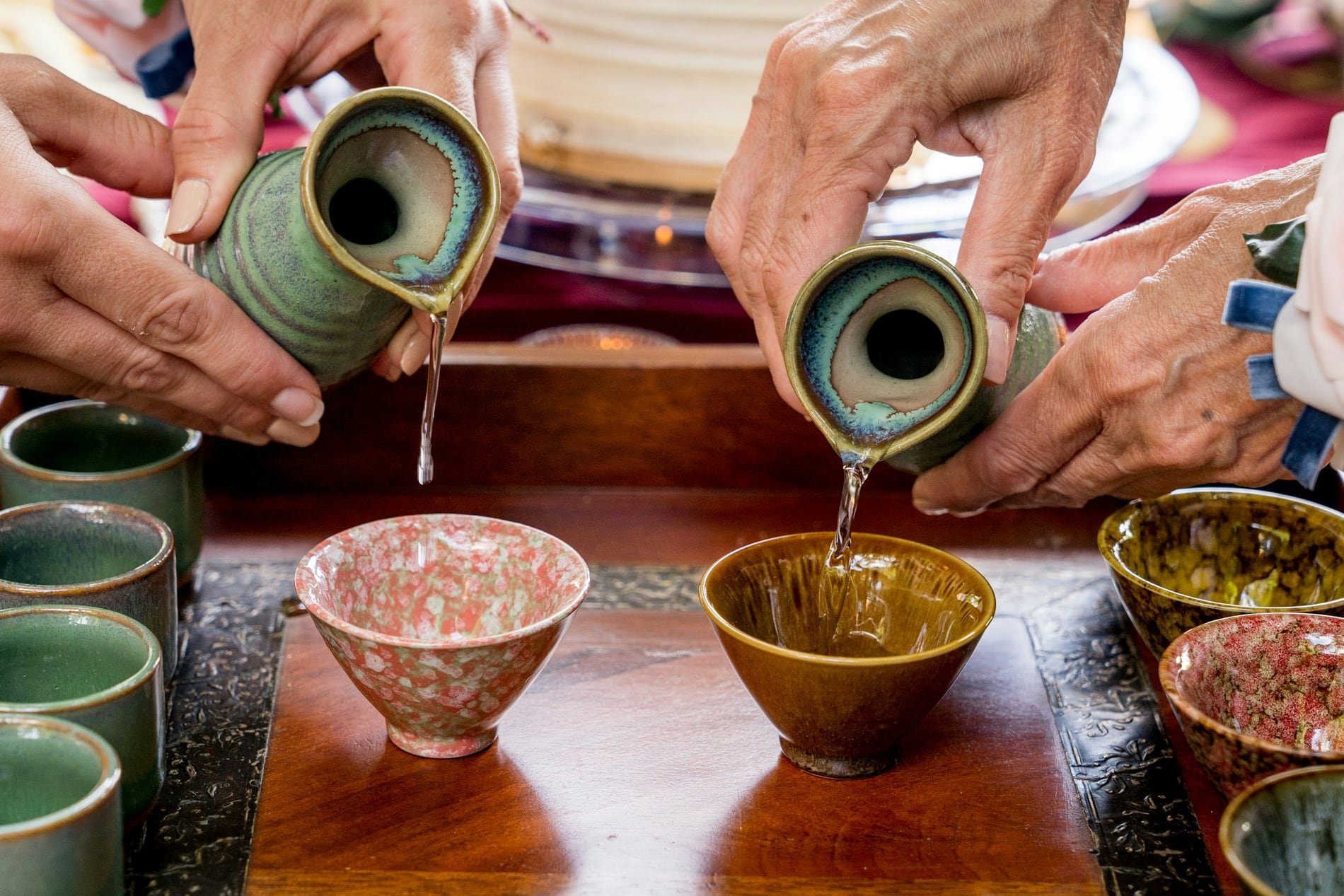Sake being poured into ceramic cups at a tasting