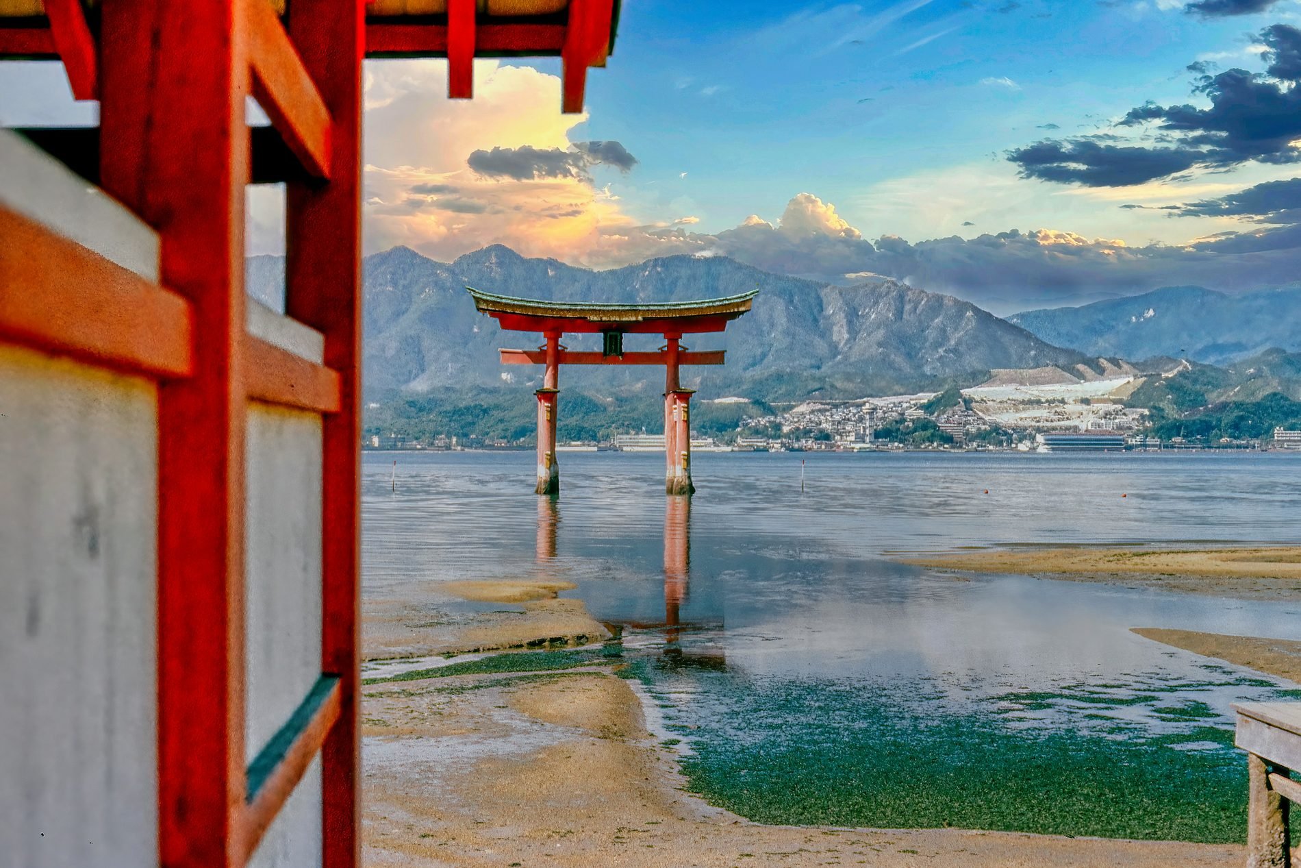A red torii gate standing in the sea at Miyajima, seen between the posts of a vermilion corridor