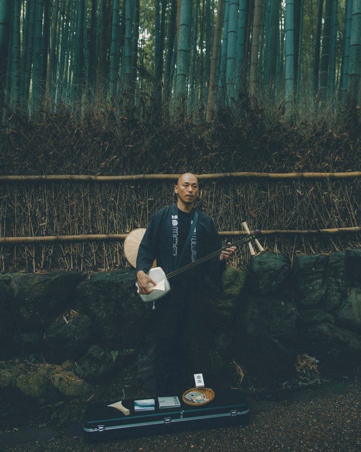 A shamisen player in a bamboo grove