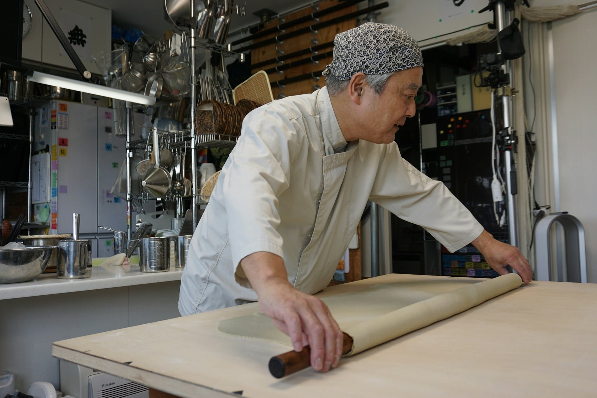 A soba master rolling out noodle dough