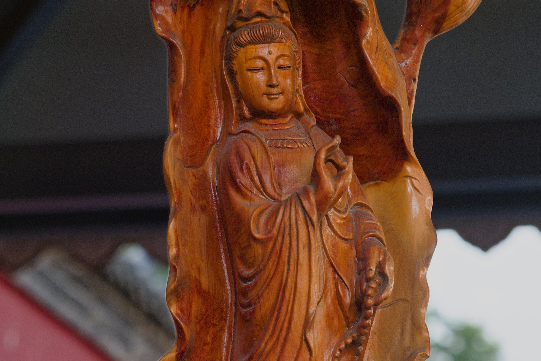 A hand-carved wooden statuette of a standing Buddhist figure