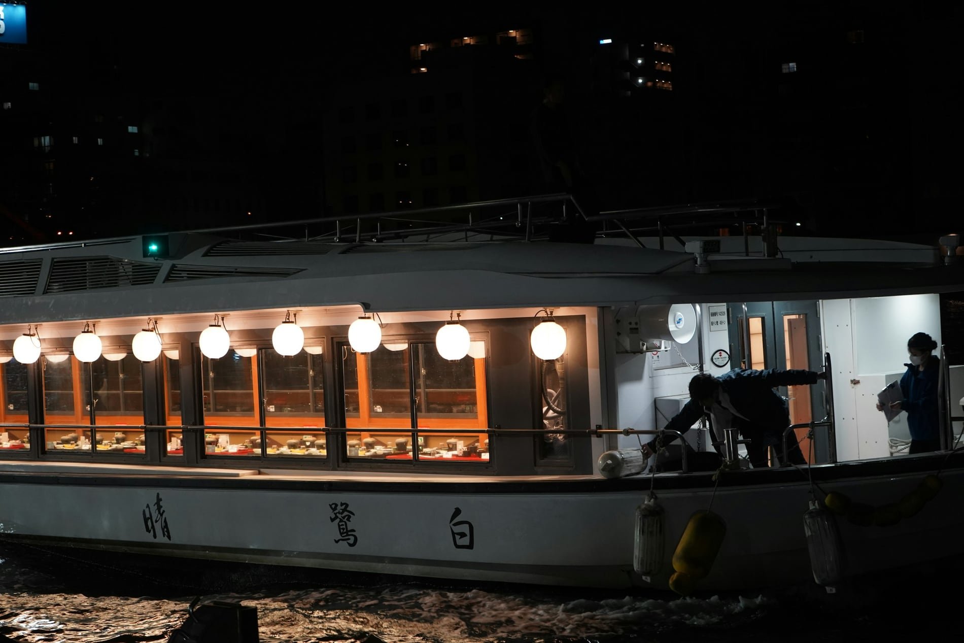 A lantern-lit Japanese pleasure boat on a river at night