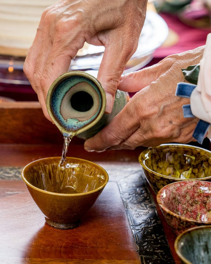 Sake being poured into ceramic cups at a tasting