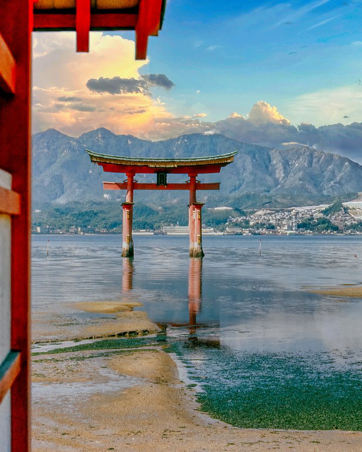 A red torii gate standing in the sea at Miyajima, seen between the posts of a vermilion corridor