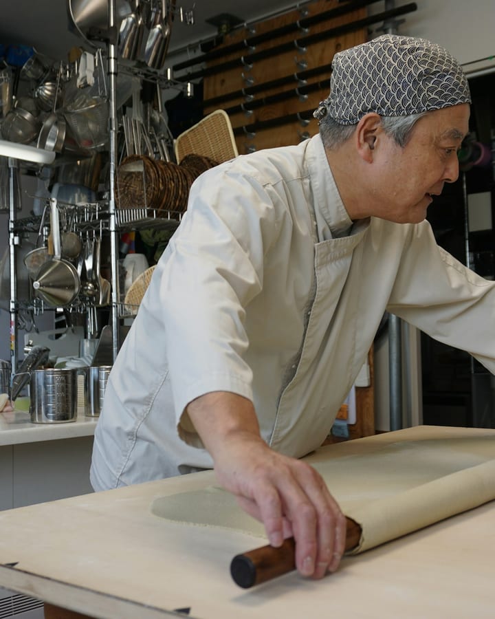 A soba master rolling out noodle dough