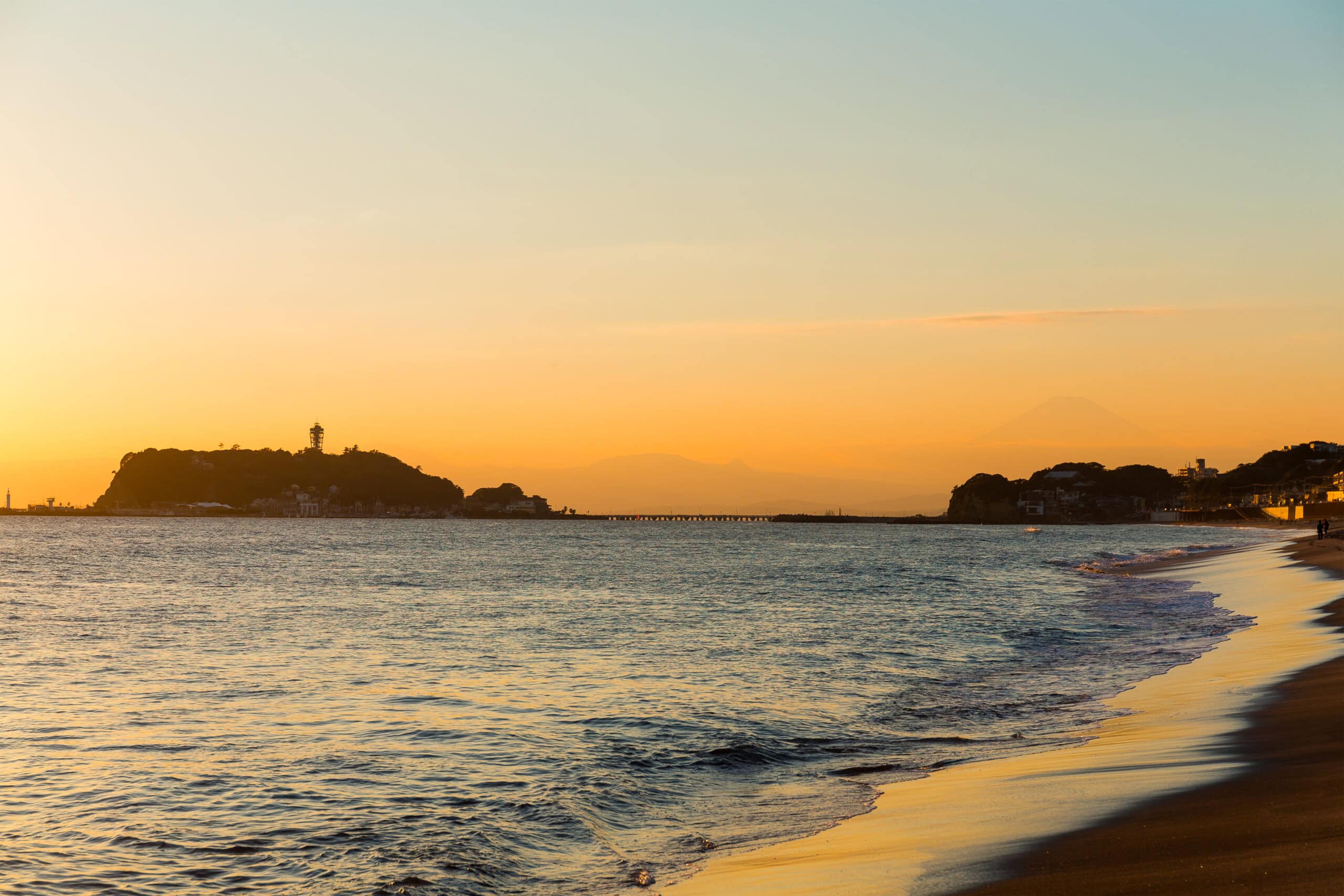 Sunset over the beach in Kamakura with Enoshima Island and Mount Fuji in the distance. Summer in japan
