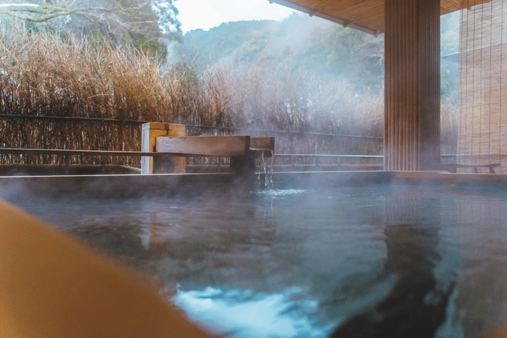 Steam rising from a traditional outdoor onsen surrounded by nature near Tokyo, Japan